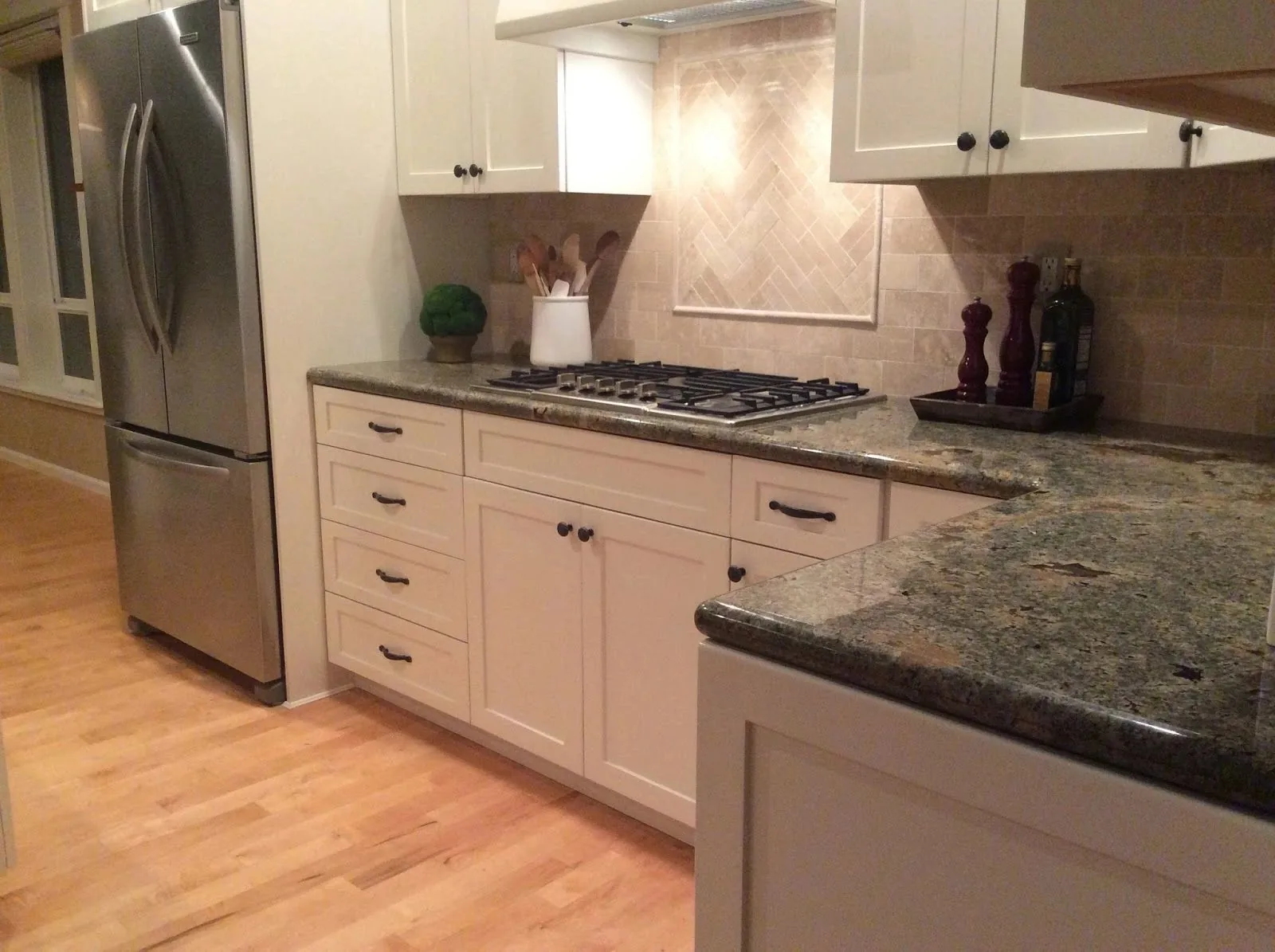 White shaker kitchen with herringbone tile backsplash and gas cooktop